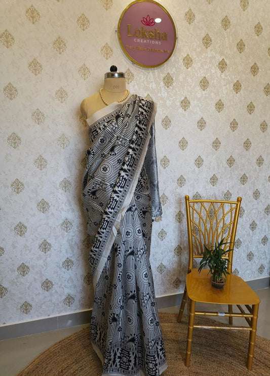 Mannequin wearing a black and white patterned saree against a decorative wall.